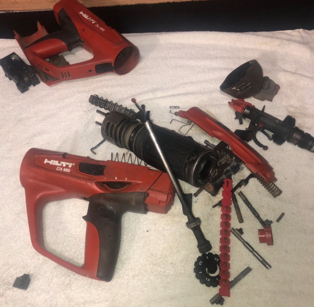 Hilti DX 460 powder-actuated tool fully disassembled for repair